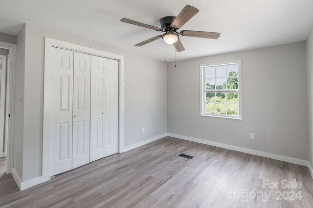 unfurnished bedroom with light hardwood / wood-style flooring, a closet, and ceiling fan