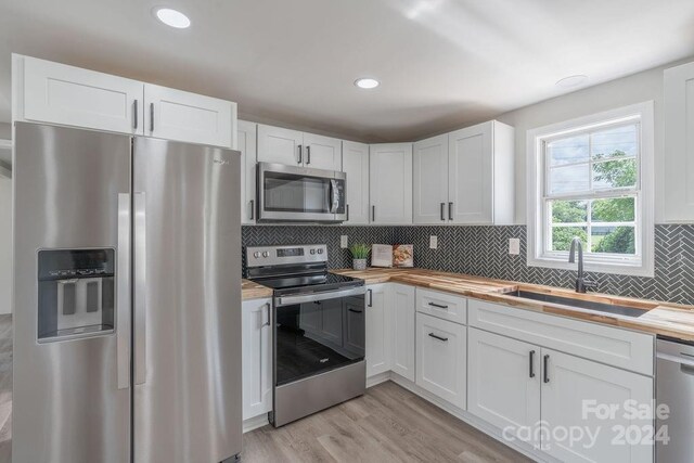 kitchen featuring stainless steel appliances, sink, white cabinets, and light hardwood / wood-style flooring