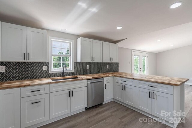 kitchen featuring sink, butcher block counters, white cabinets, stainless steel dishwasher, and kitchen peninsula