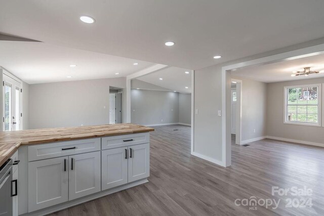 kitchen featuring white cabinetry, lofted ceiling, butcher block counters, and light hardwood / wood-style floors