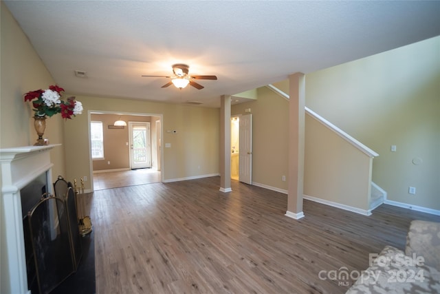 unfurnished living room featuring ceiling fan, hardwood / wood-style flooring, and a textured ceiling