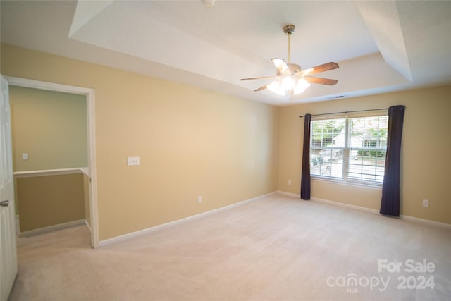 carpeted empty room featuring ceiling fan and a raised ceiling