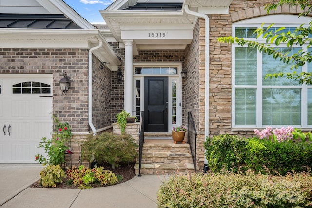 view of exterior entry with stone siding, brick siding, and an attached garage