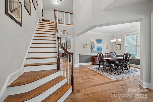 interior space with stairway, light wood-style floors, ornamental molding, a chandelier, and baseboards