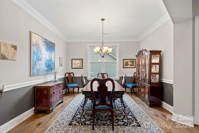 dining room featuring baseboards, light wood finished floors, crown molding, and an inviting chandelier