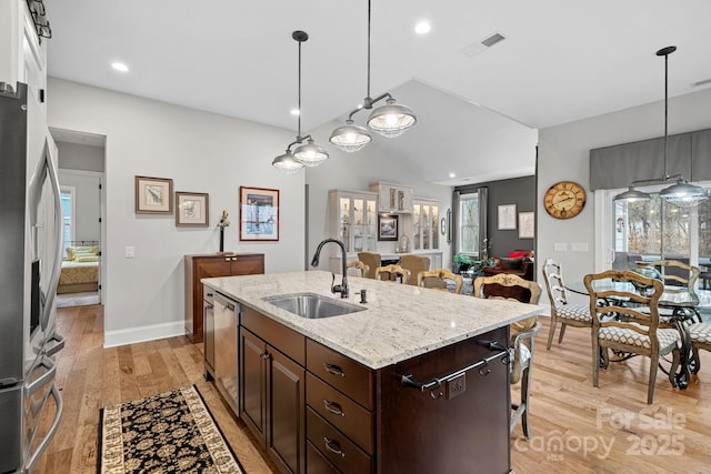 kitchen with dark brown cabinetry, visible vents, open floor plan, decorative light fixtures, and a sink