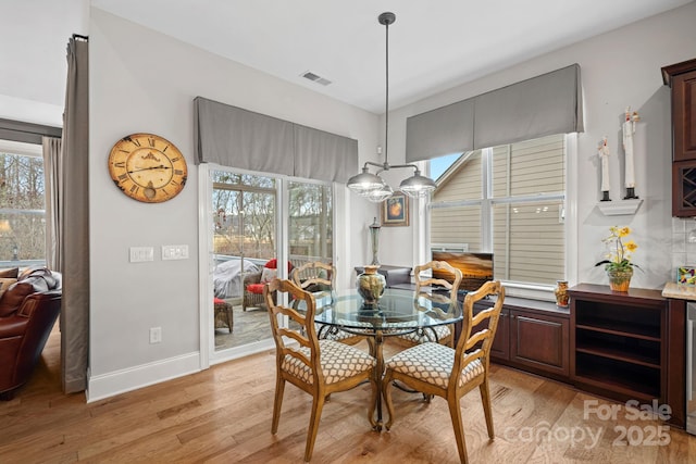 dining room with light wood-style flooring, visible vents, and baseboards