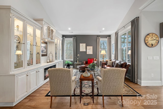 dining room featuring light wood-style floors, a wealth of natural light, vaulted ceiling, and baseboards