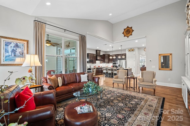 living area with baseboards, dark wood finished floors, lofted ceiling, ceiling fan, and a healthy amount of sunlight