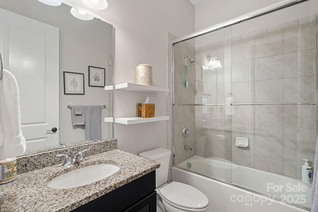 bathroom with shower / bath combination with glass door, vanity, and toilet