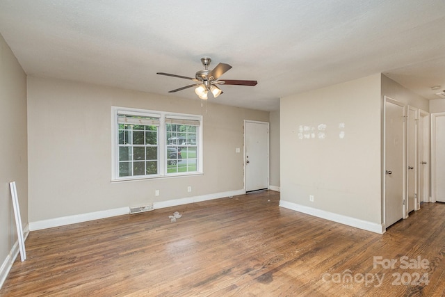 unfurnished room with a ceiling fan, visible vents, baseboards, and wood finished floors