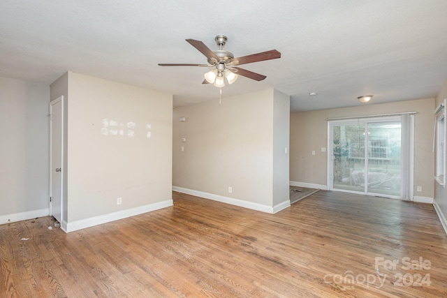 spare room with wood finished floors, a ceiling fan, and baseboards