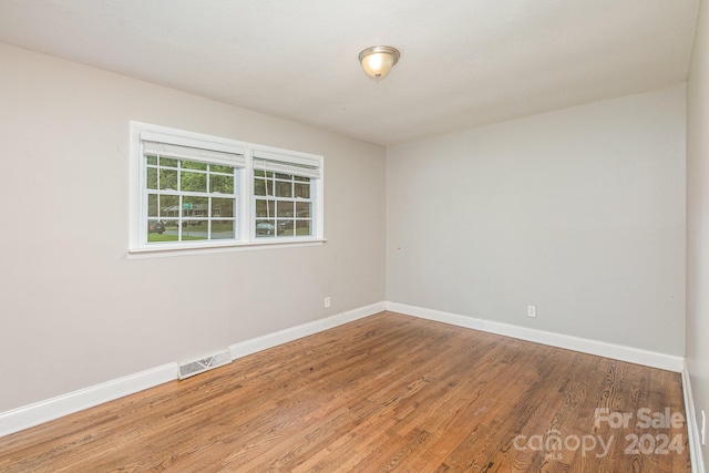 empty room with baseboards, visible vents, and wood finished floors