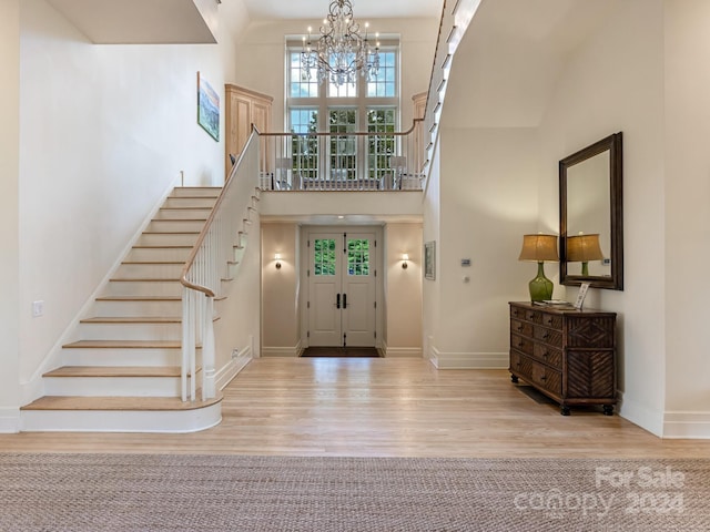 entrance foyer featuring light hardwood / wood-style floors, a notable chandelier, and a towering ceiling