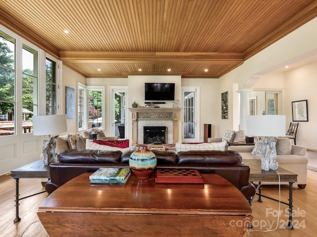 living room featuring crown molding, light wood-type flooring, beamed ceiling, ornate columns, and wooden ceiling