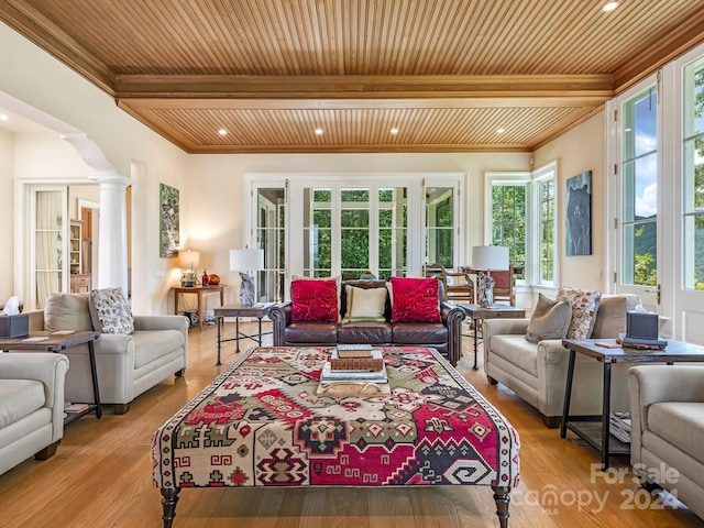 living room featuring crown molding, light hardwood / wood-style flooring, beamed ceiling, ornate columns, and wooden ceiling