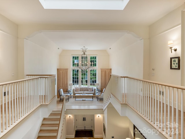 hallway featuring high vaulted ceiling, a chandelier, and a skylight