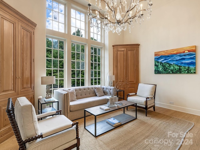 living room featuring a notable chandelier, light wood-type flooring, and a high ceiling