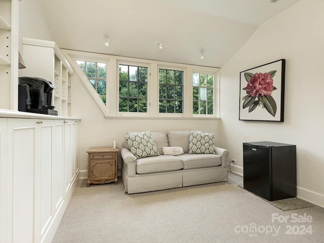 living area with lofted ceiling, a healthy amount of sunlight, and light colored carpet