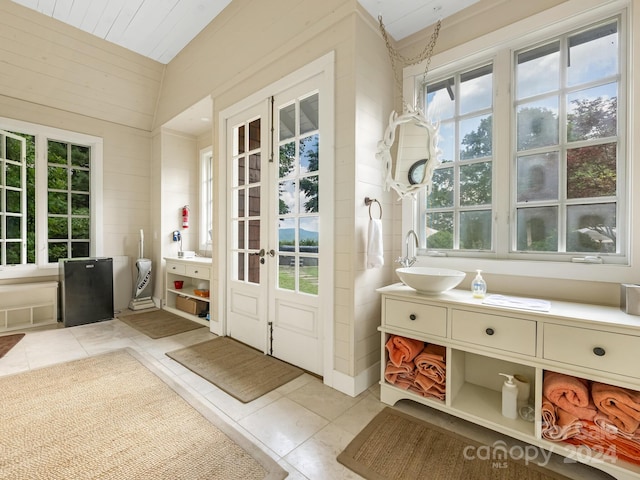 doorway to outside with sink, light tile patterned flooring, a healthy amount of sunlight, and lofted ceiling