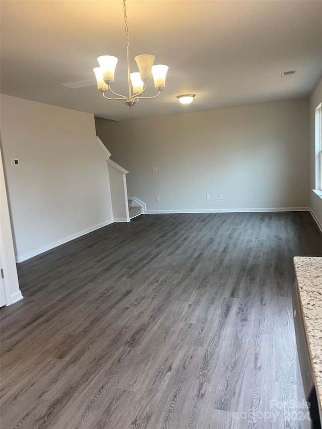 unfurnished living room with a chandelier and dark wood-type flooring