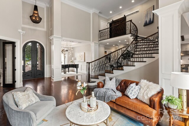 living room featuring french doors, crown molding, a high ceiling, hardwood / wood-style floors, and ornate columns