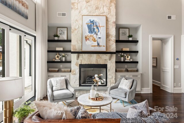 sitting room with built in features, a high ceiling, a fireplace, and dark hardwood / wood-style floors