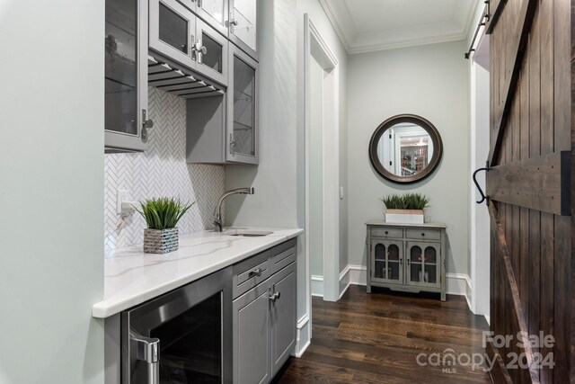 bar featuring a barn door, gray cabinets, decorative backsplash, dark hardwood / wood-style flooring, and wine cooler