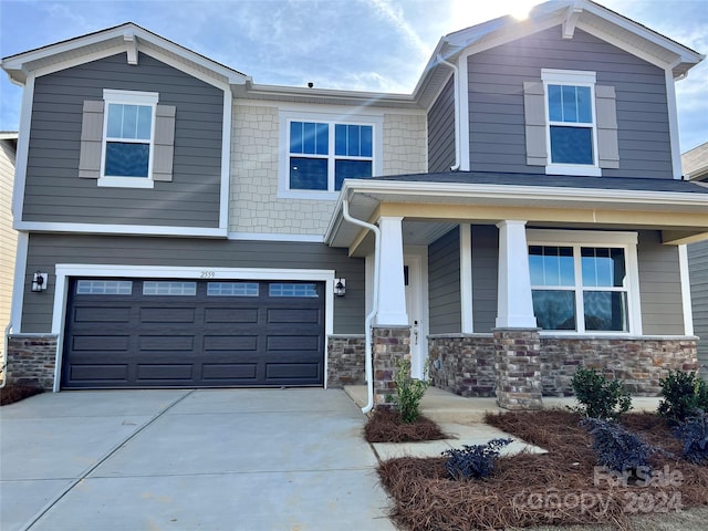 craftsman-style house with a garage, stone siding, a porch, and concrete driveway