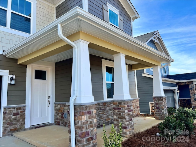 doorway to property with covered porch and a garage