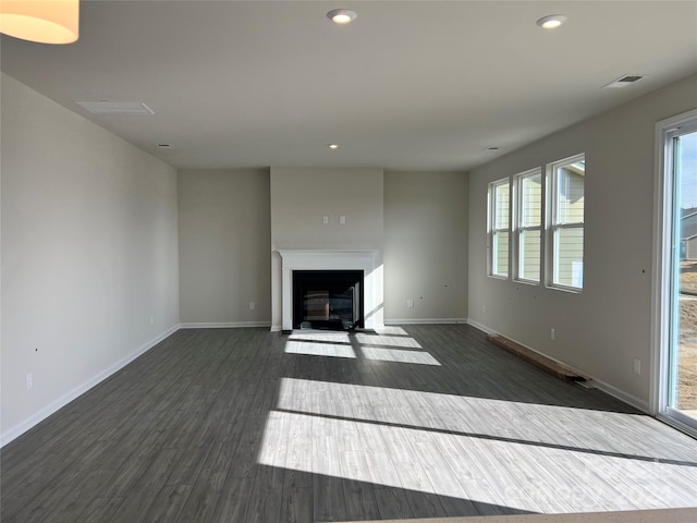 unfurnished living room featuring plenty of natural light and dark wood-type flooring