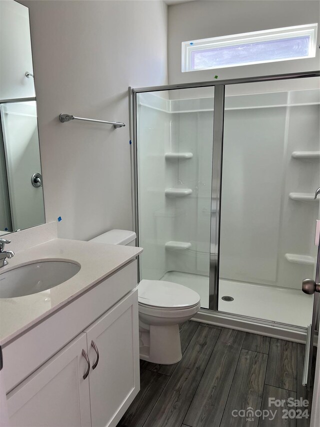 bathroom with a shower with shower door, vanity, wood-type flooring, and toilet