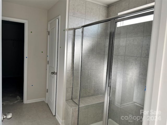 bathroom with a shower with shower door and tile patterned flooring