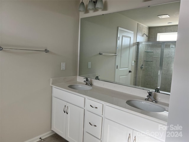 bathroom featuring a shower with shower door and double vanity