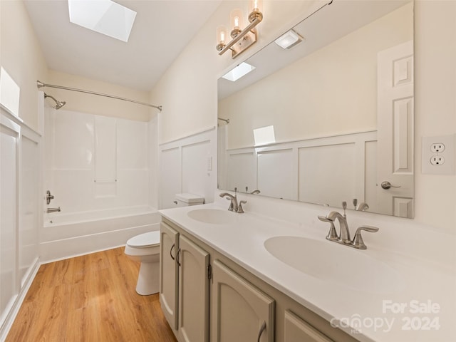 full bathroom featuring tub / shower combination, a skylight, toilet, hardwood / wood-style flooring, and dual bowl vanity