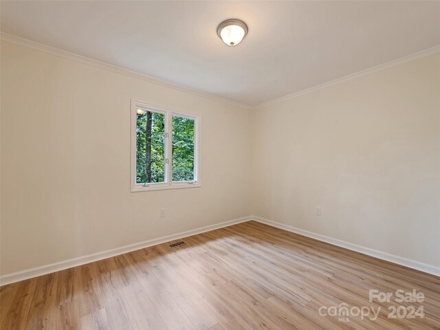 spare room featuring light hardwood / wood-style flooring and ornamental molding