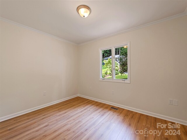 empty room with light hardwood / wood-style flooring and ornamental molding