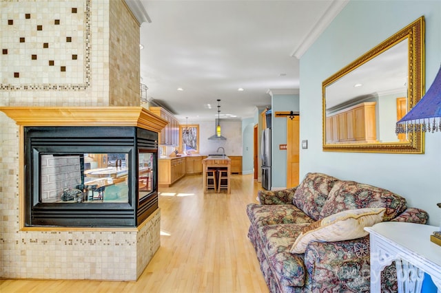 living area featuring ornamental molding, recessed lighting, a multi sided fireplace, and light wood finished floors