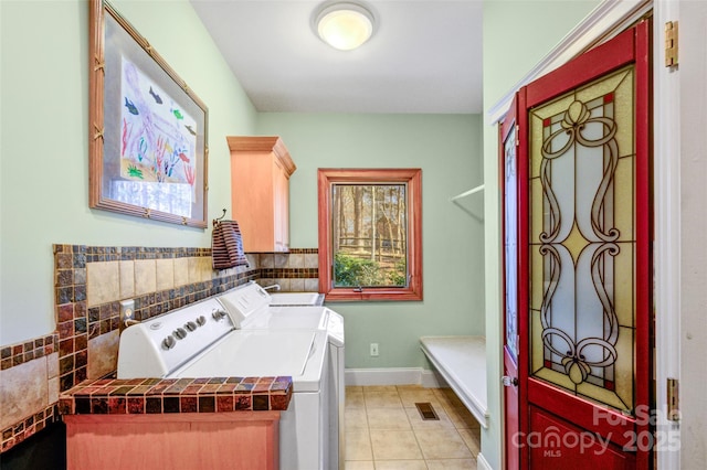 clothes washing area featuring washing machine and clothes dryer, light tile patterned floors, a healthy amount of sunlight, laundry area, and baseboards