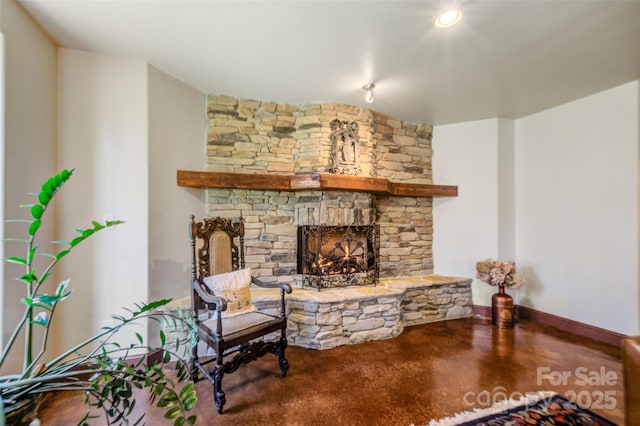 living area featuring a fireplace, finished concrete floors, and baseboards