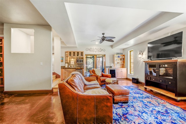 living room with ceiling fan, bar, beverage cooler, baseboards, and finished concrete floors