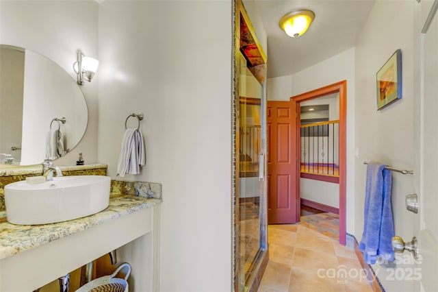 full bath featuring a shower with door, vanity, baseboards, and tile patterned floors