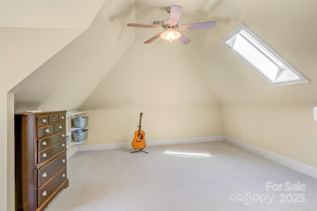 additional living space featuring carpet floors, baseboards, lofted ceiling with skylight, and a ceiling fan