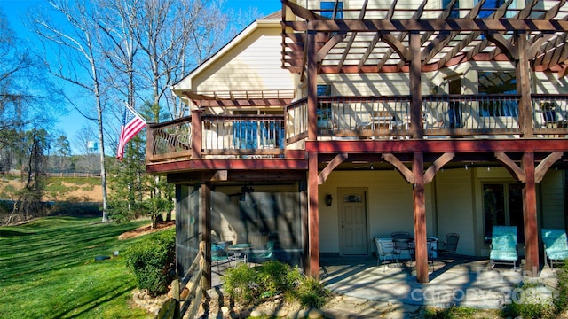 back of house with a wooden deck, a lawn, a pergola, and a patio