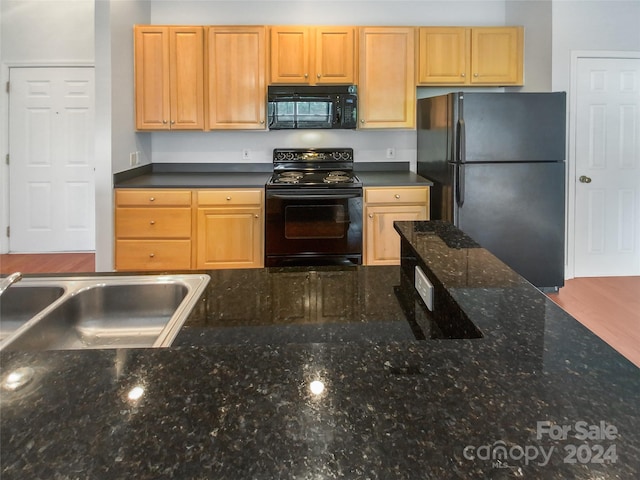 kitchen with dark stone counters, sink, light brown cabinets, and black appliances