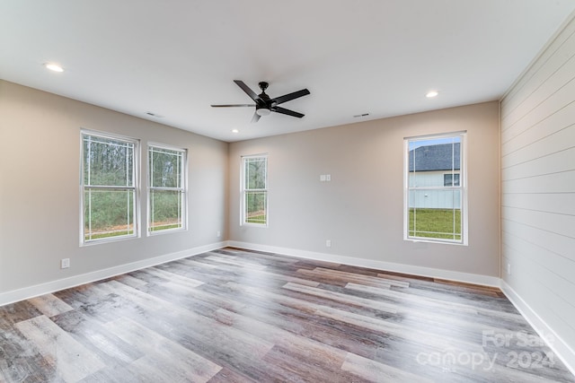 empty room with ceiling fan, hardwood / wood-style flooring, and a healthy amount of sunlight