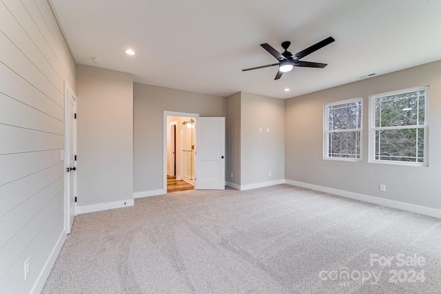 unfurnished bedroom featuring light carpet, ensuite bath, and ceiling fan