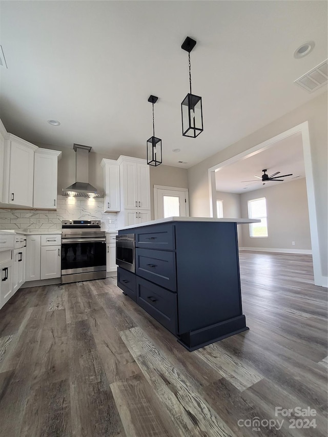 kitchen with tasteful backsplash, wall chimney range hood, electric stove, hanging light fixtures, and hardwood / wood-style flooring