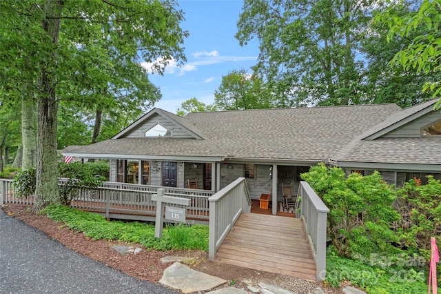 view of front facade with stone siding and roof with shingles