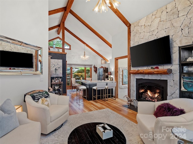 living area featuring high vaulted ceiling, a stone fireplace, wood finished floors, a chandelier, and beamed ceiling